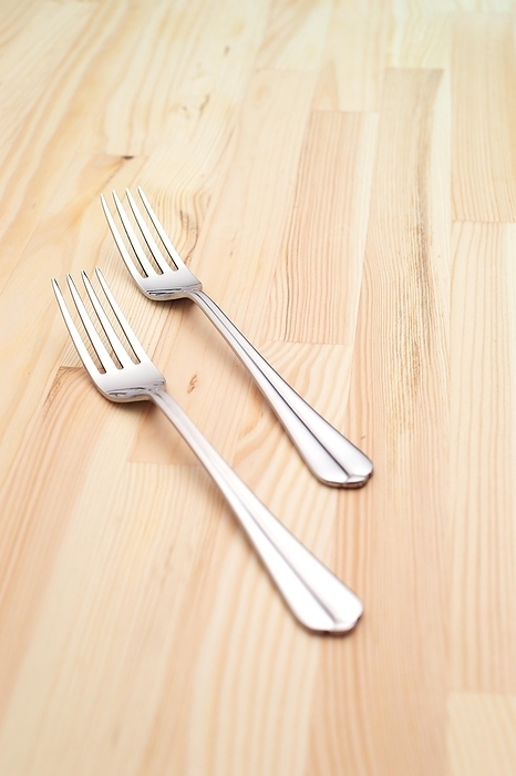 Two fork on a kitchen pinewood table closeup, by keko64