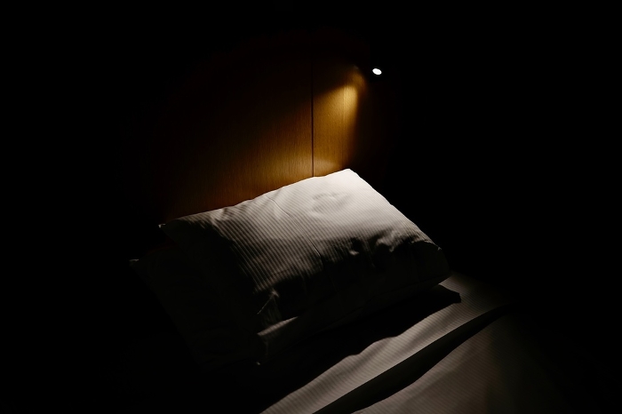 Pillow lit by bed site lamp in dark bedroom