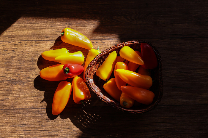 Various colored peppers in baskets on a wood background