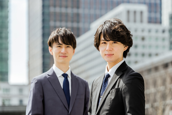 Two Japanese men in young business suits looking serious for the camera in a business district (People)