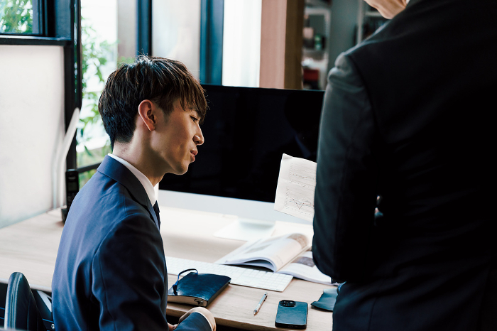 Profile of a Japanese man, a supervisor in a managerial position, checking a report from a subordinate in his office (People)