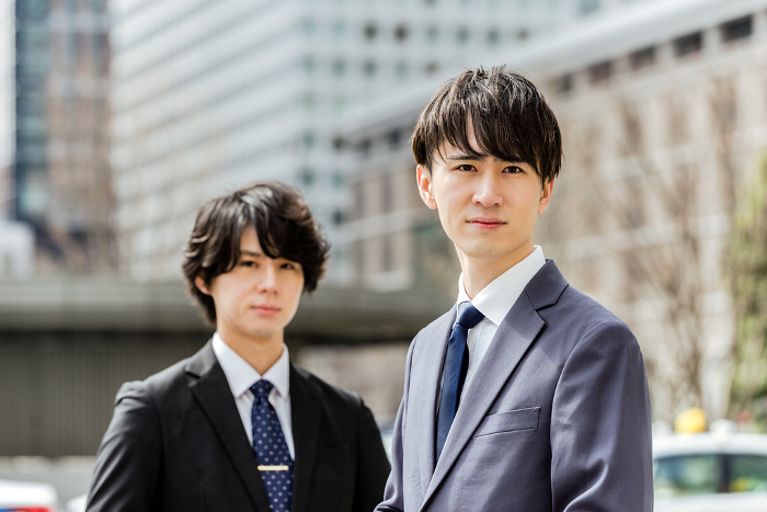 Two Japanese men in young business suits looking serious for the camera in the city (People)