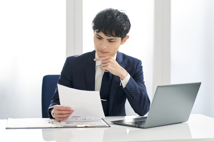 Japanese businessman examining work documents (Male / People)