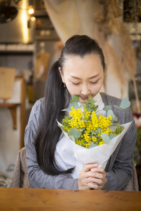 Woman holding a bouquet of mimosa and eucalyptus