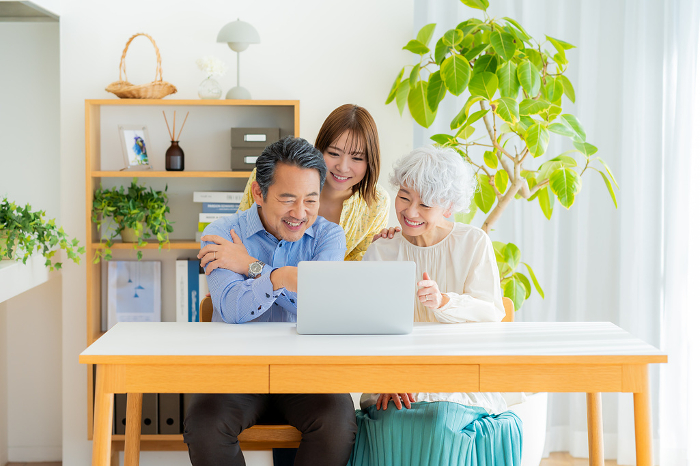 Japanese senior couple and their child looking at a computer (People)