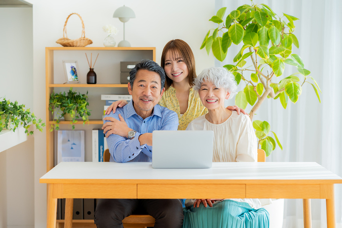 Japanese senior couple and their child looking at a computer (People)