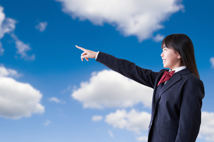 Japanese female student pointing under a blue sky (People)