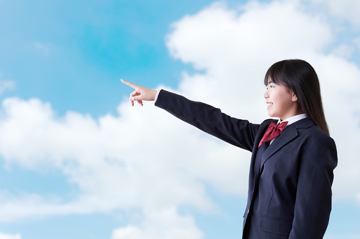 Japanese female student pointing under a blue sky (People)