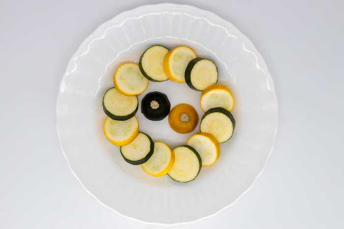 Raw zucchini sliced into rounds and arranged on a round white plate