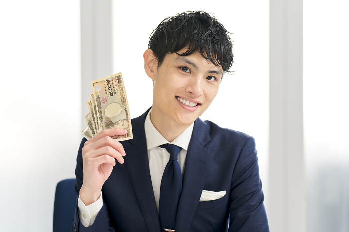 Smiling Japanese businessman holding money (Male / People)