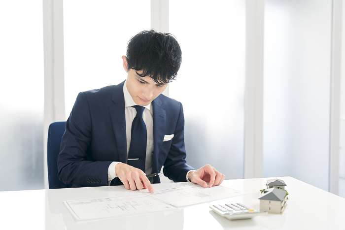 Japanese businessman thinking about real estate layout （Male / People)