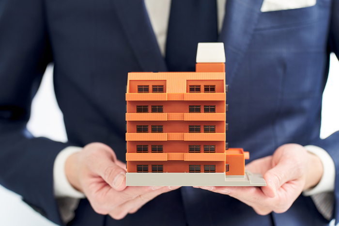 Businessman's hand holding a model of an apartment building