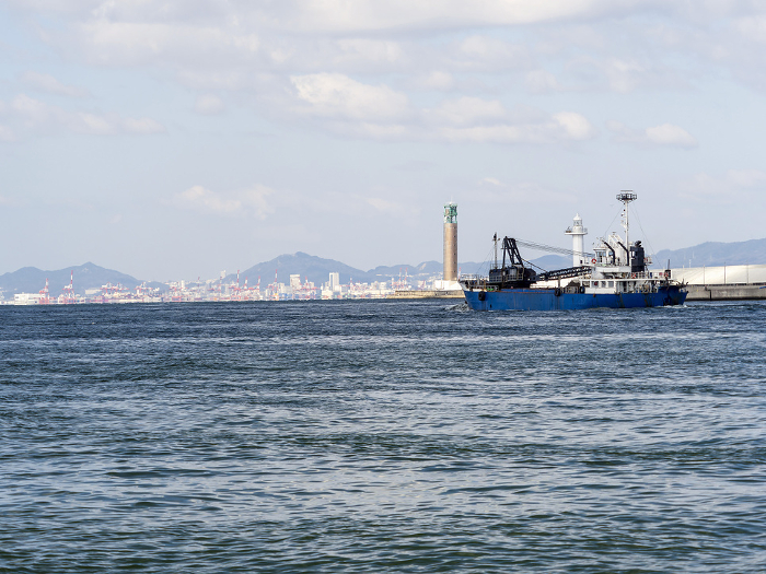 A gravel barge sailing through Osaka Port and a view of Kobe Port
