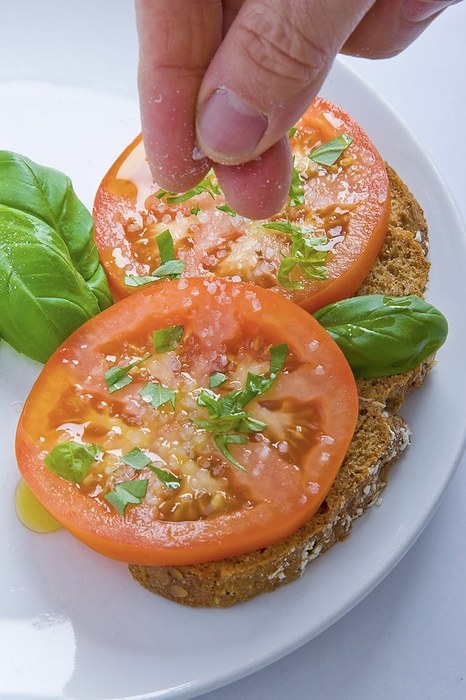 Man's Hands Adding Salt to Basil and Tomatoes Sandwich