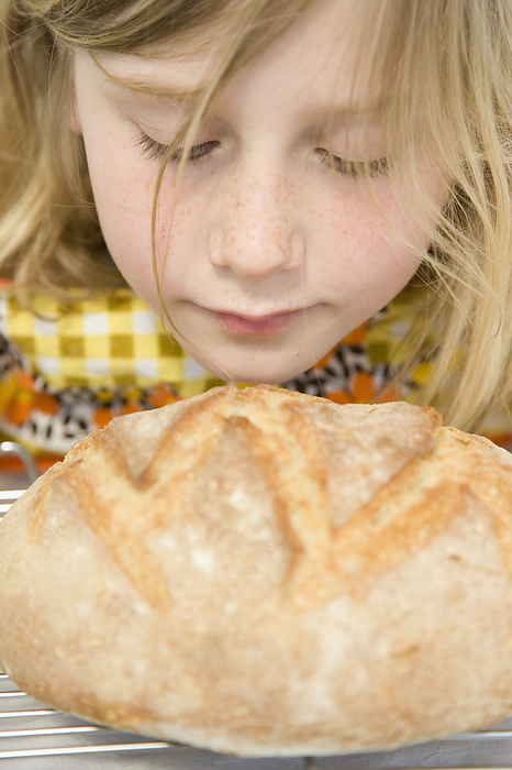 Young Girl Smelling a Loaf of Bread