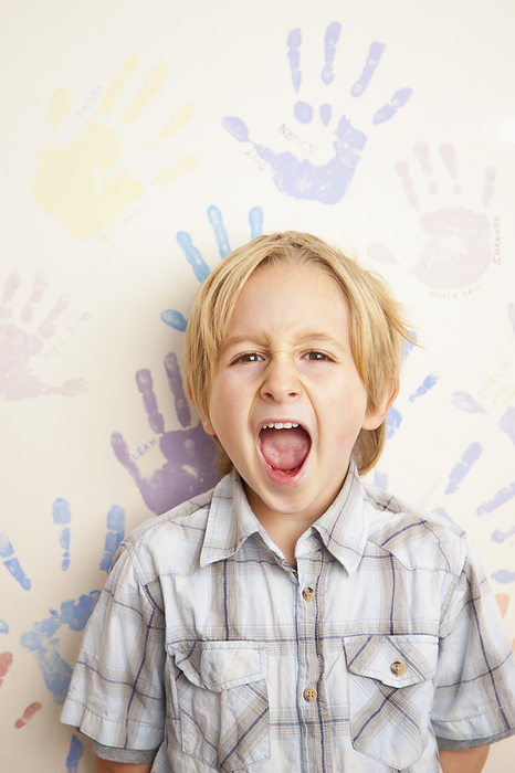 Screaming Boy Standing in front of Wall Covered in Handprints