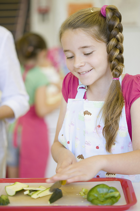 Young girl in cookery class cutting vegetables
