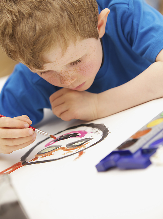Young boy lying on floor painting with watercolors