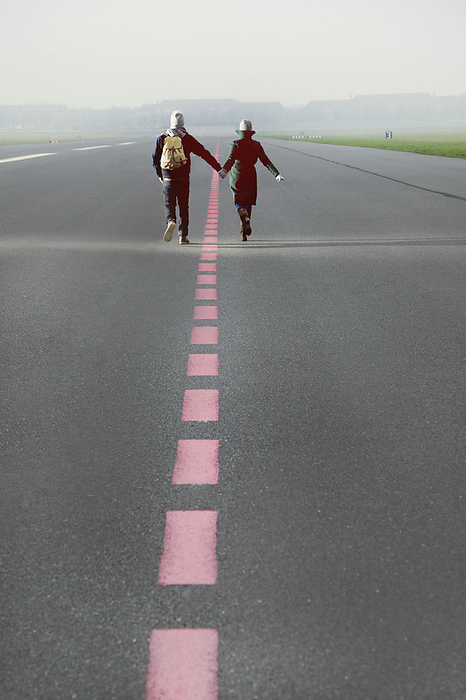 Couple Running along Airport Runway Holding Hands, Rear View
