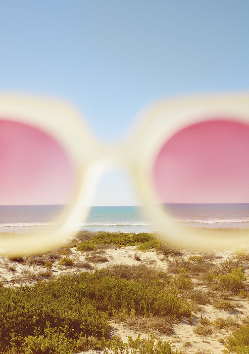 Cropped View of Rose-Colored Sunglasses with Beach in the background