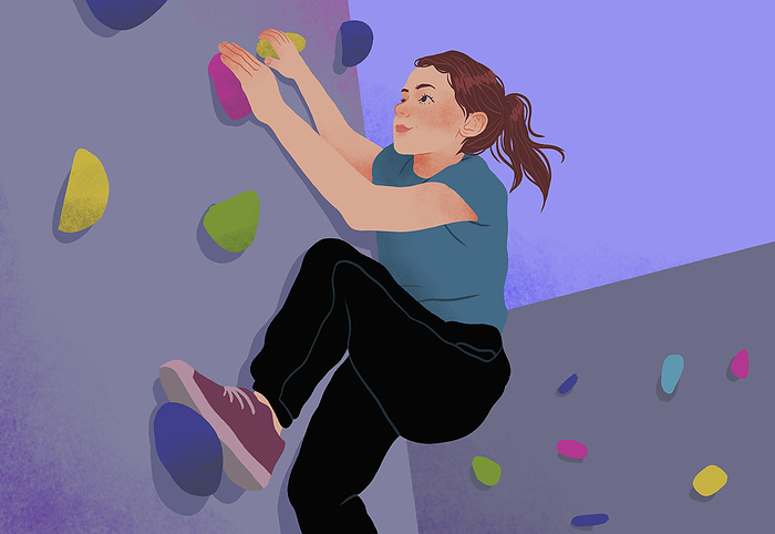 Determined teenage girl rock climbing on rock climbing wall