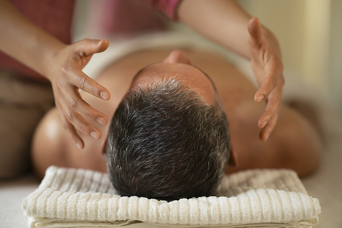 Man receiving energy medicine head massage in spa