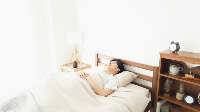 Japanese man waking up when his alarm clock rings.