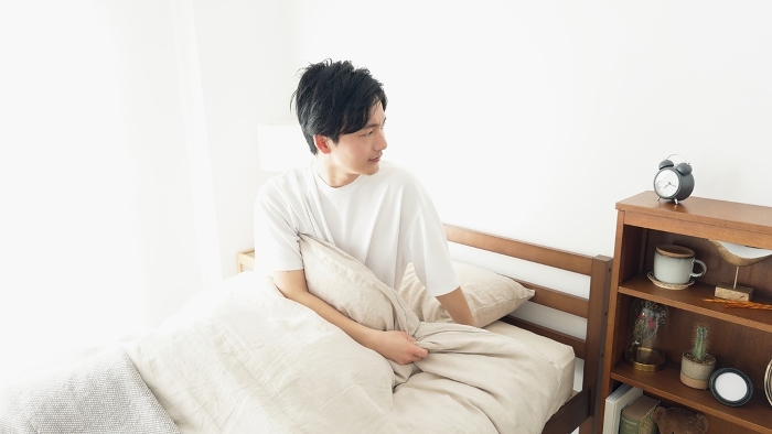 Japanese man waking up when his alarm clock rings.