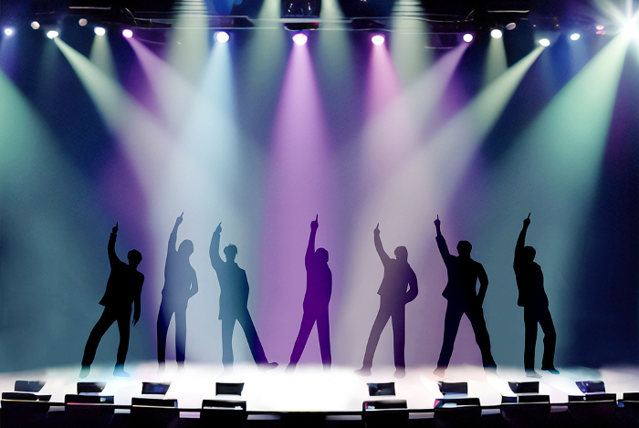 Seven male silhouettes dance on a spotlit stage with index fingers raised.