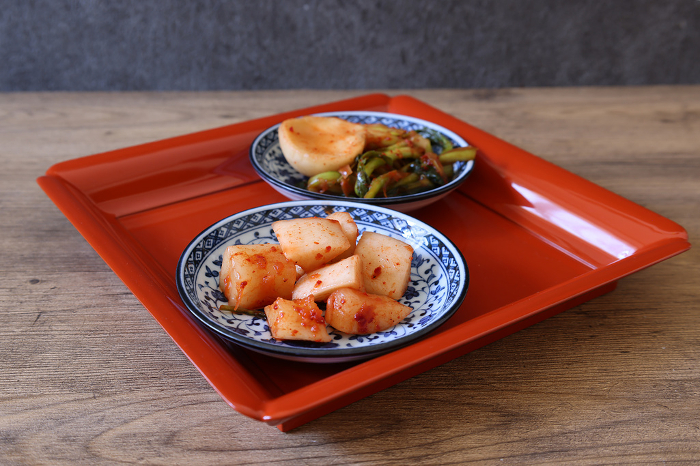Turnip kimchi and radish kimchi served on a red tray