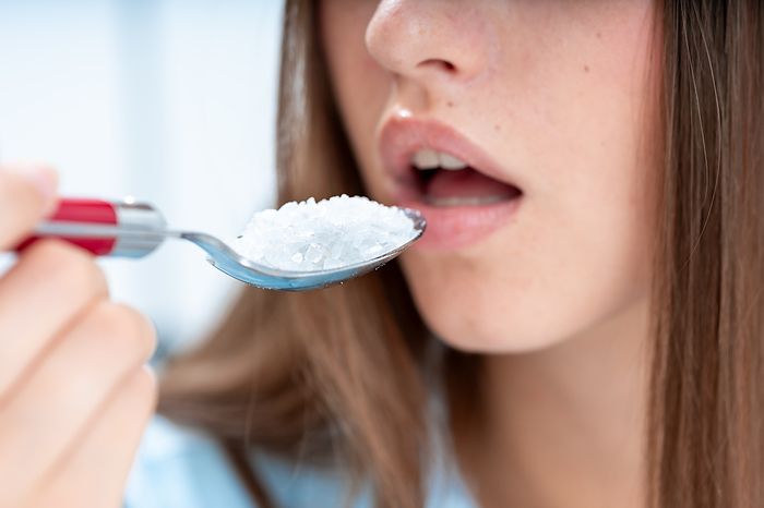 Woman eating a spoon of salt Woman eating a spoon of salt. This could represent concept of unhealthy eating., by WLADIMIR BULGAR SCIENCE PHOTO LIBRARY