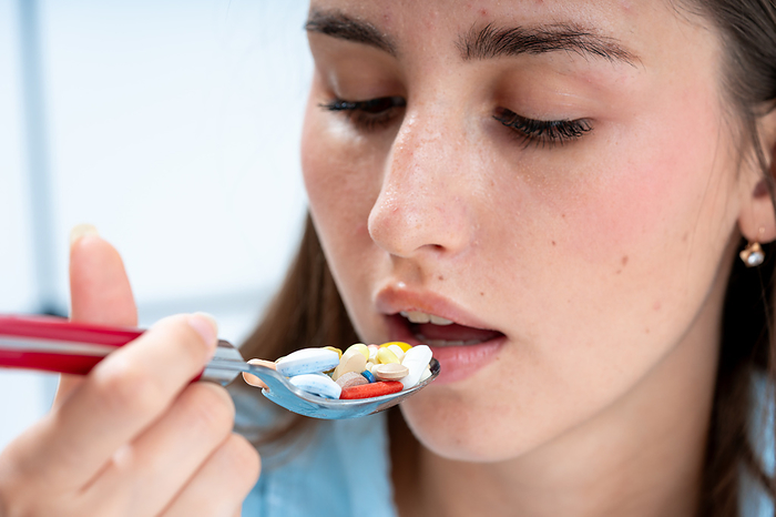 Woman eating spoon filled with pills Woman eating spoon filled with pills. This could the concept of uncontrolled medication use and drug addiction., by WLADIMIR BULGAR SCIENCE PHOTO LIBRARY