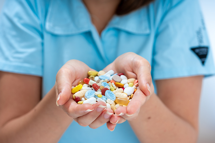 Woman holding pile of pills Woman holding pile of pills. This could represent issue with drug addiction., by WLADIMIR BULGAR SCIENCE PHOTO LIBRARY