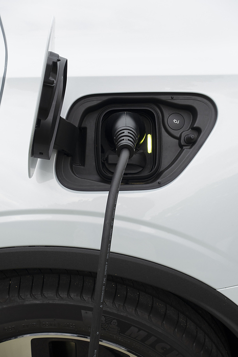 Electric car being charged Electric car charging with a cable plugged in., by DR NEIL OVERY SCIENCE PHOTO LIBRARY