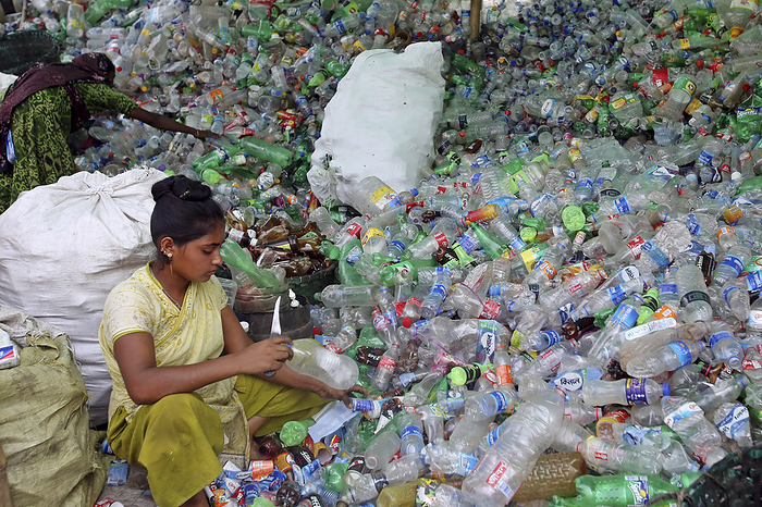 Plastic bottle recycling, Dhaka, Bangladesh Women sorting through a mound of empty plastic bottles at a plastic bottle recycling plant in Dhaka, Bangladesh., by HABIBUR RAHMAN SCIENCE PHOTO LIBRARY