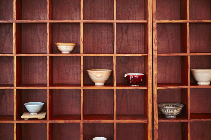 Tea sets and teacups lined up in a cupboard