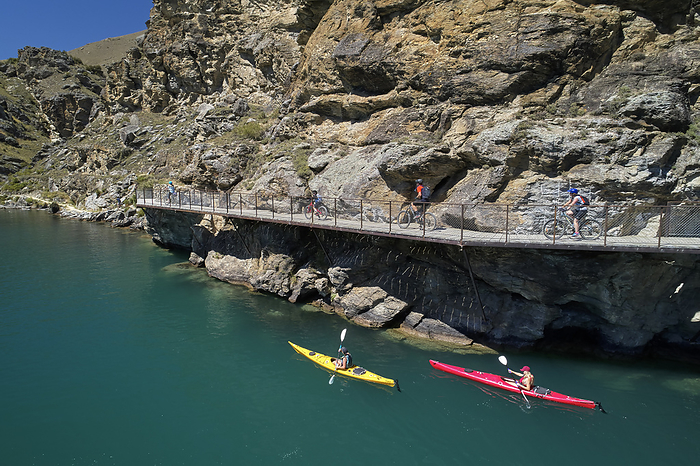 New Zealand Cyclists on cantilever bridge on Lake Dunstan Cycle Trail, and kayakers, Lake Dunstan, near Cromwell, Central Otago, South Island, New Zealand   drone aerial