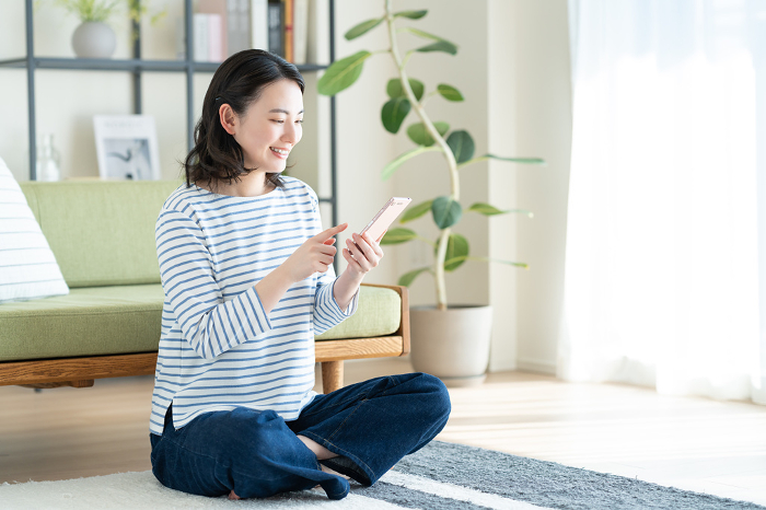 Young Japanese woman using a smartphone in her living room (People)