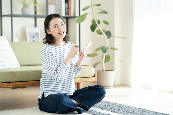 Young Japanese woman using a smartphone in her living room (People)