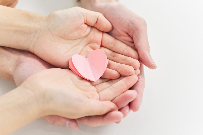 Hands of a man and a woman placing a heart object
