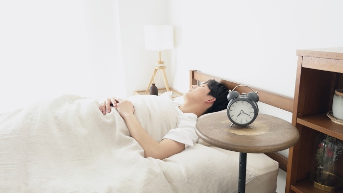 Japanese man sleeping with alarm clock set (People)