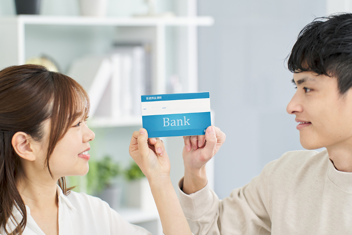 Smiling Japanese man and woman holding bank books (People)