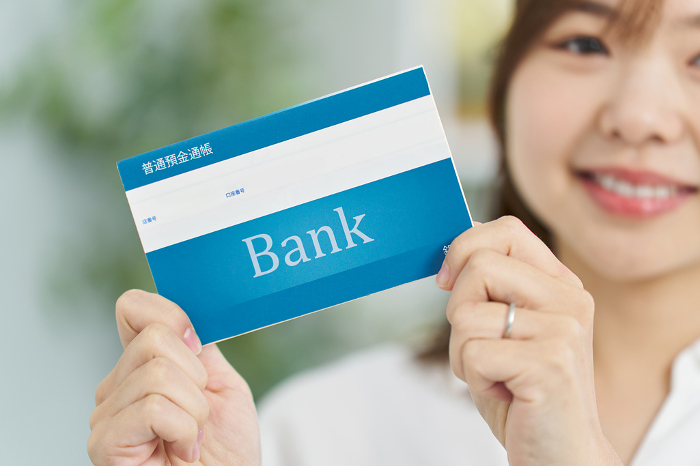 A woman holding a bank book with a smile on her face