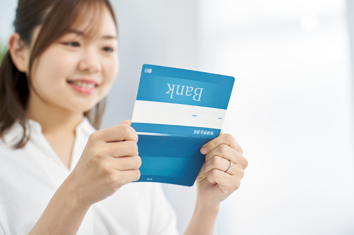 Japanese woman looking at her bankbook with a smile (People)