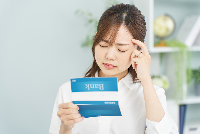 Japanese woman having trouble looking at her bank book (People)