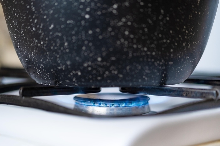 Closeup view of a pan on a gas hob, cooking on a gas stove, by Aleksei Isachenko