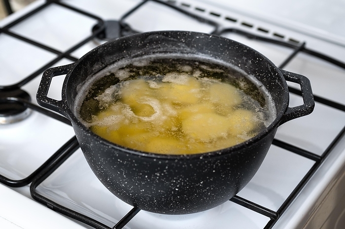 Cooking halved potato in a pot with boiling water on a gas stove, by Aleksei Isachenko