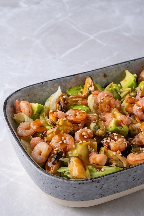 Closeup view of bowl with iceberg lettuce salad with shrimp, mussels and avocado, by Aleksei Isachenko