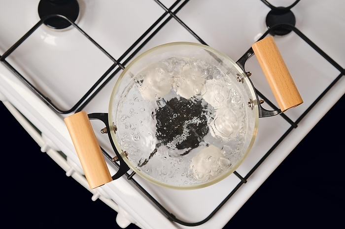Top view of transparent glass saucepan with boiling eggs on a gas stove, by Aleksei Isachenko
