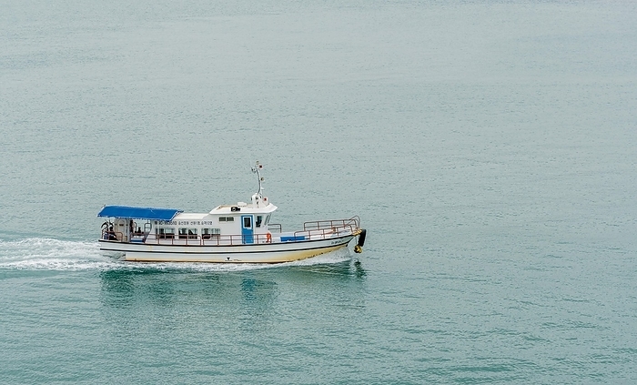 Small ferry boat making its way across ocean harbor waters, South Korea, Asia, by aminkorea
